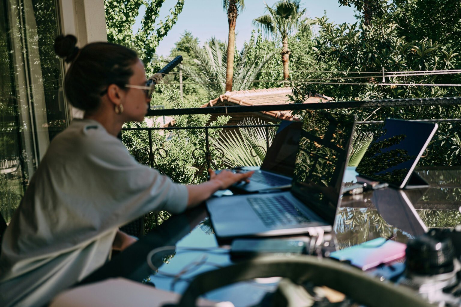 Working remotely from a villa terrace surrounded by palms